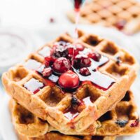 Syrup being poured onto orange cranberry waffles.