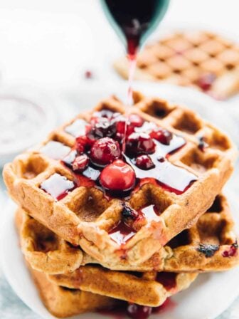 Syrup being poured onto orange cranberry waffles.