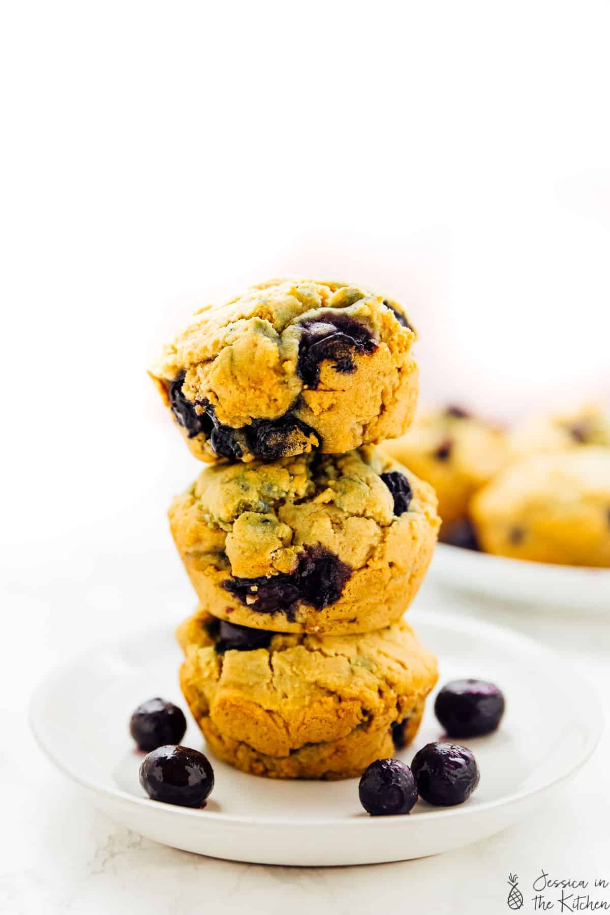 Three vegan blueberry muffins stacked in a plate.