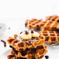 Syrup being drizzled on a stack of banana bread waffles.