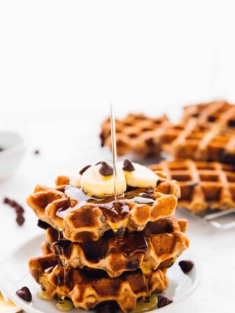 Syrup being drizzled on a stack of banana bread waffles.