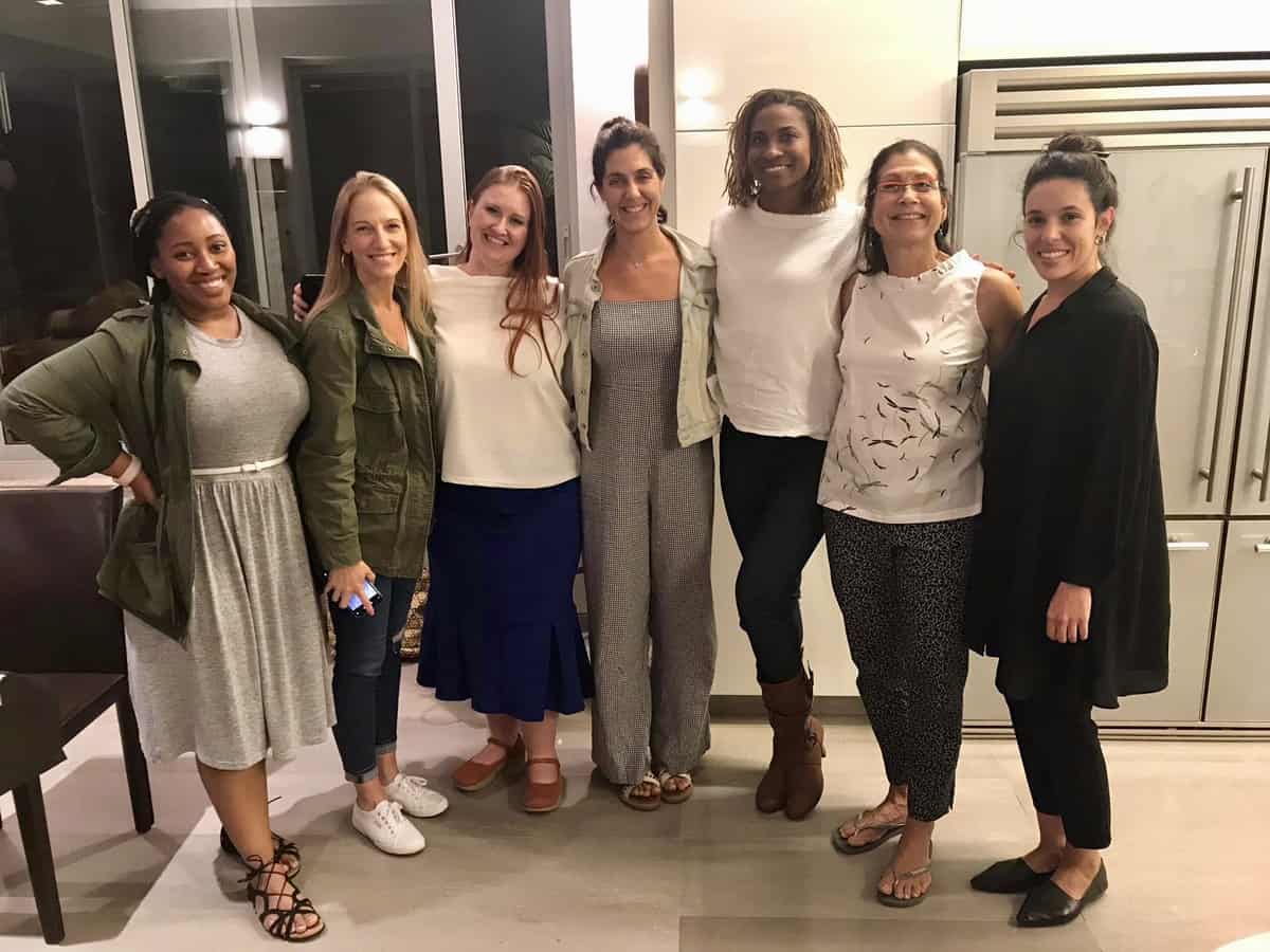 Jessica and friends smiling to camera in a kitchen.