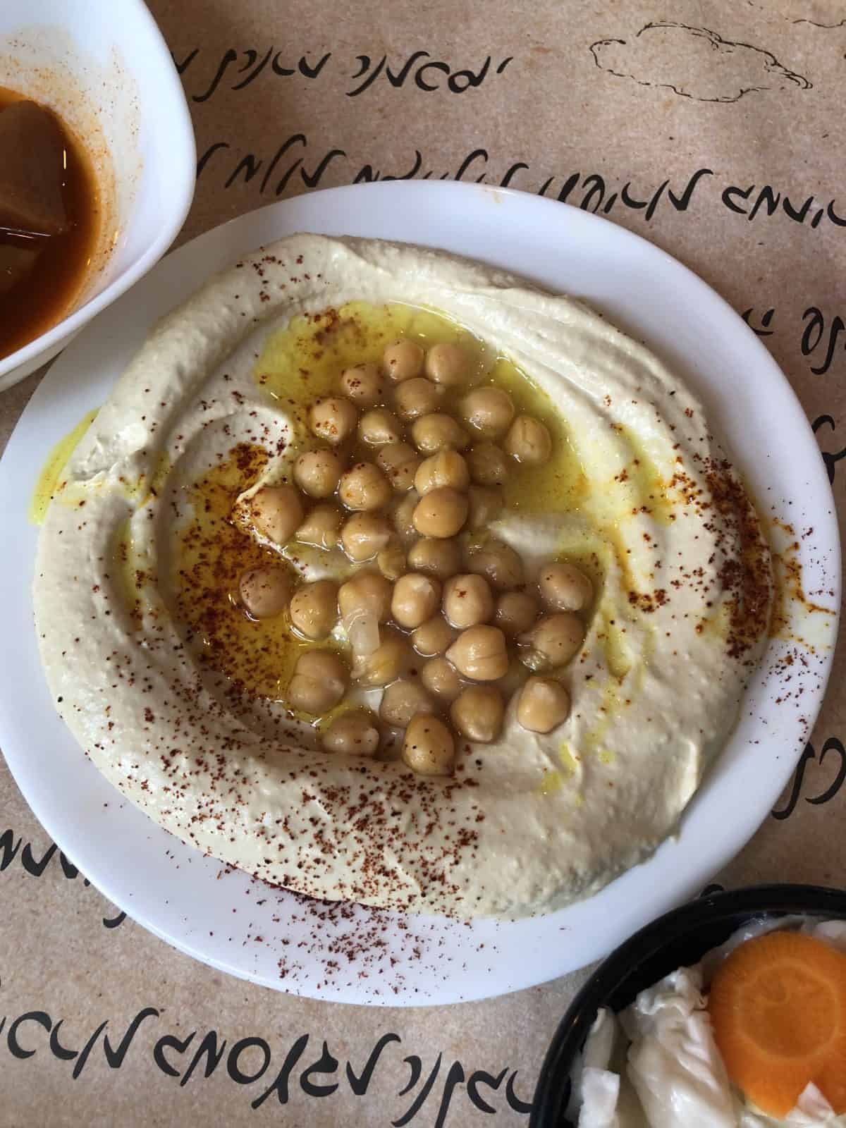 Top down view of a bowl of hummus, topped with chickpeas. 