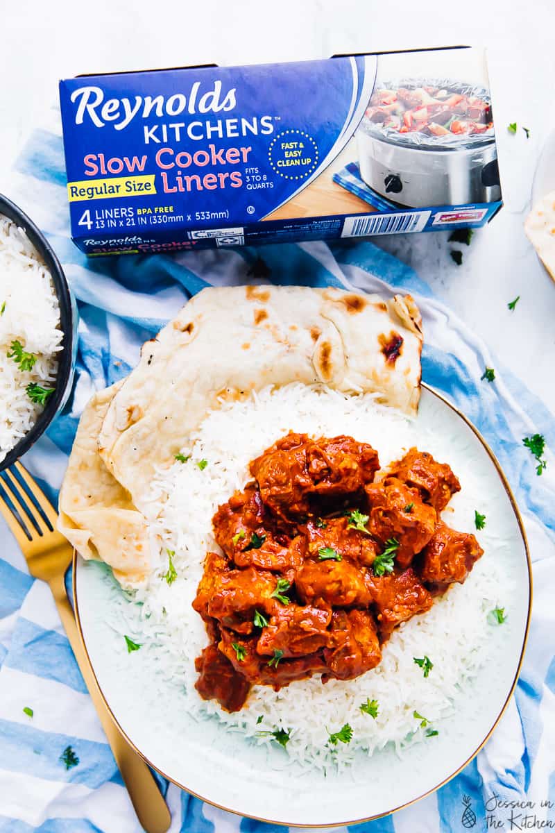 Slow cooker tofu butter chicken on a plate next to a pack of slow cooker liners. 