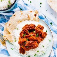 Overhead view of tofu butter chicken on a plate with rice on the side.