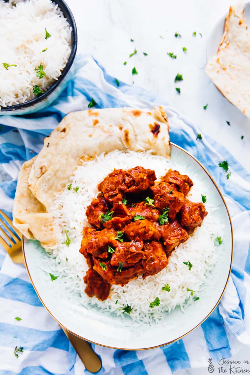 Top down view slow cooker tofu butter chicken on a bed of rice with naan bread. 