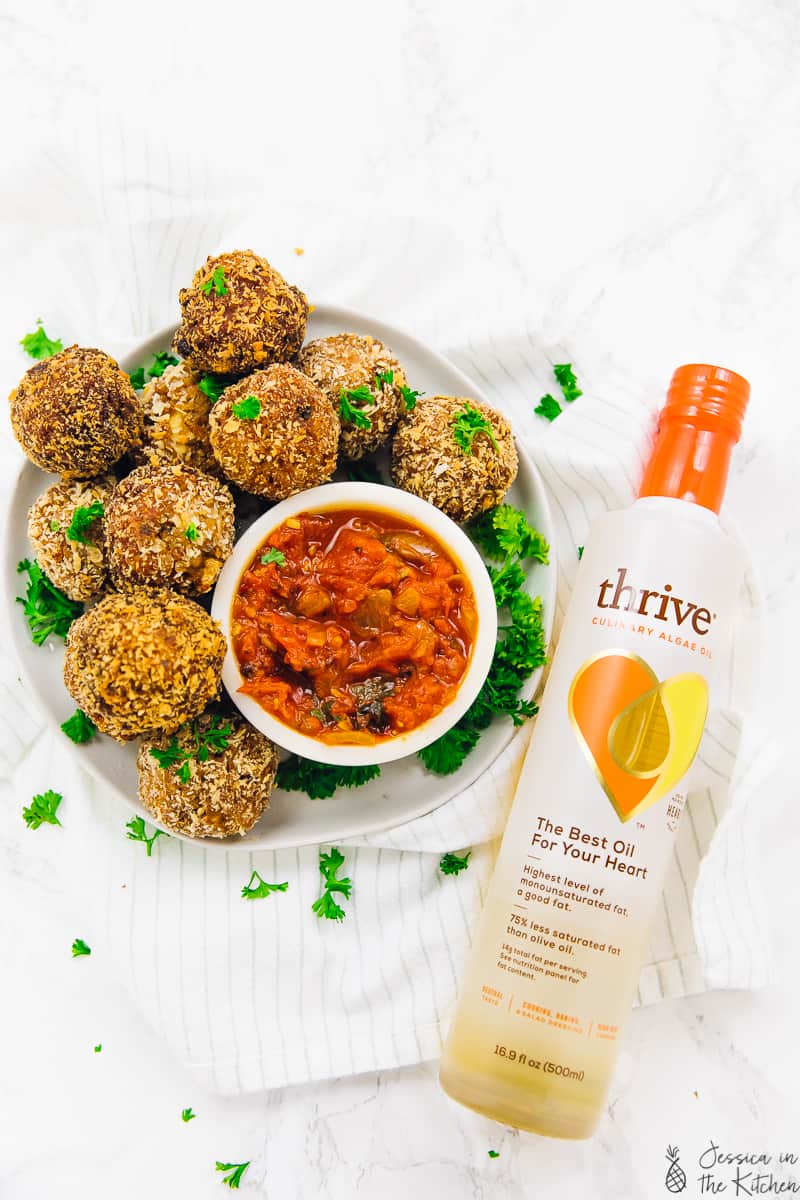 Top down view of arancini balls, dipping sauce and a bottle of algae oil.