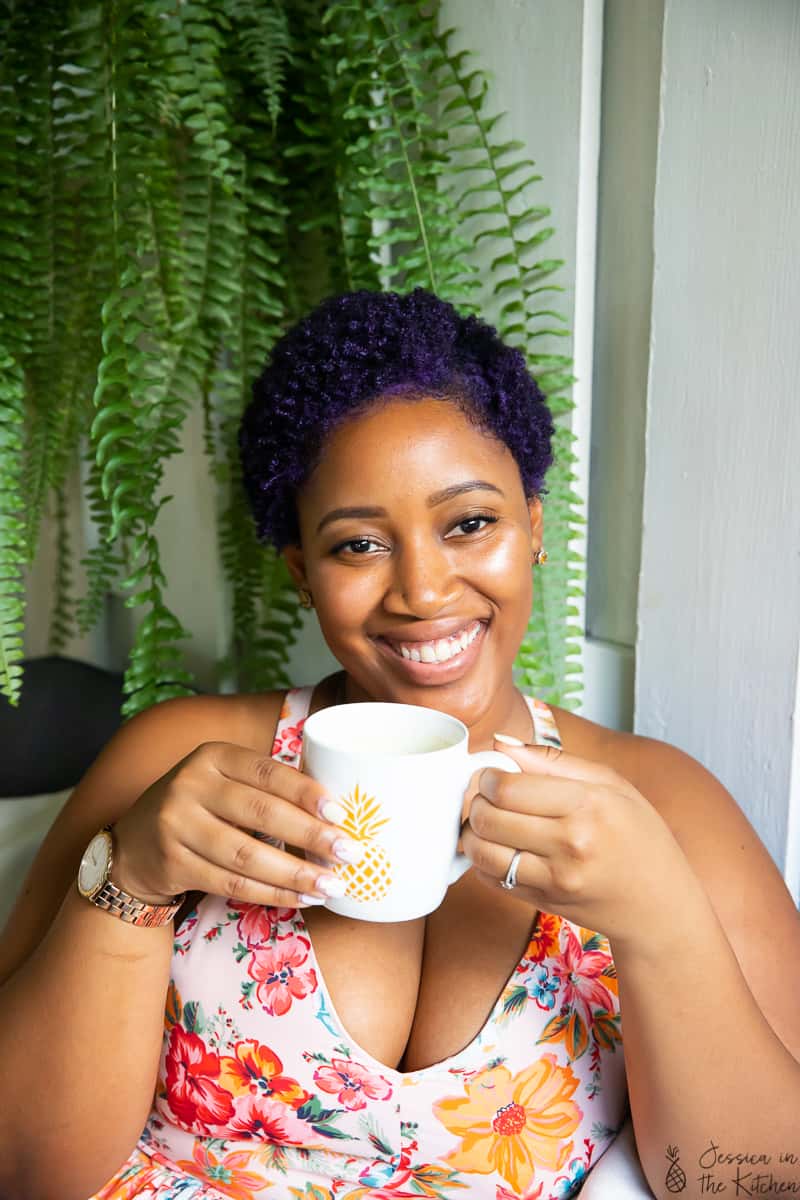 Jessica holding a mug and smiling to camera. 