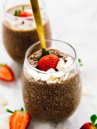 A spoon sticking into a glass of chocolate chia pudding.