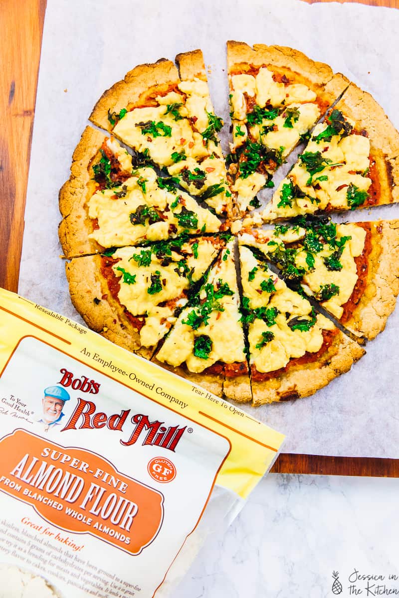 Overhead view of vegan pizza with a pack of almond flour next to it. 