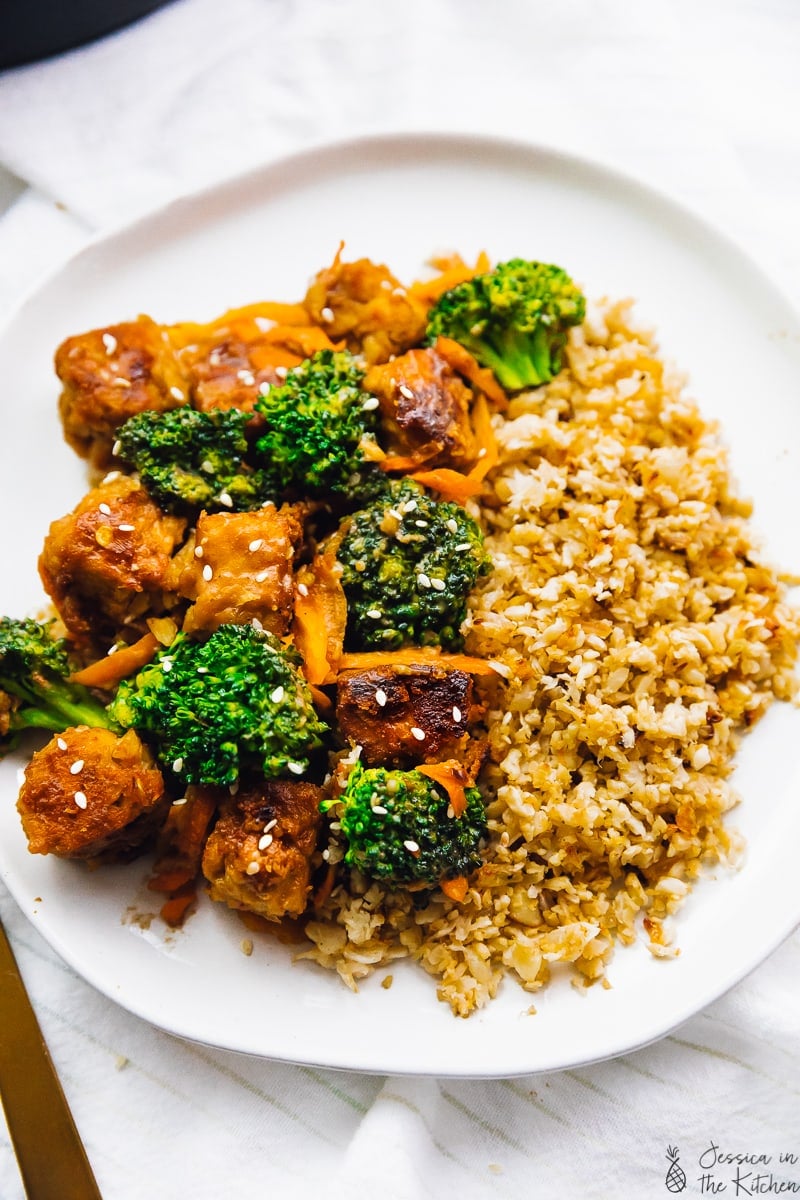 Top down view of tempeh stir fry on a white plate. 