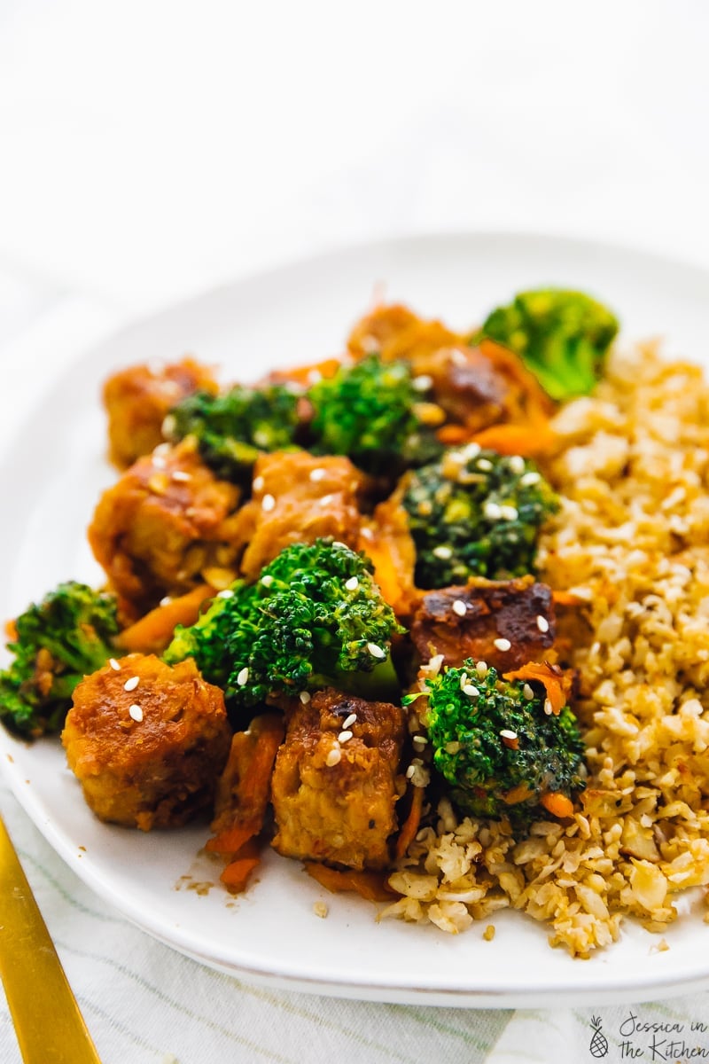 Close up of tempeh stir fry on a white plate. 