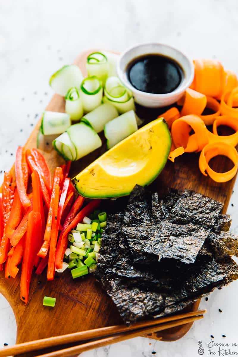 Avocado, peppers, cucumber, carrots and seaweed on a wooden board. 