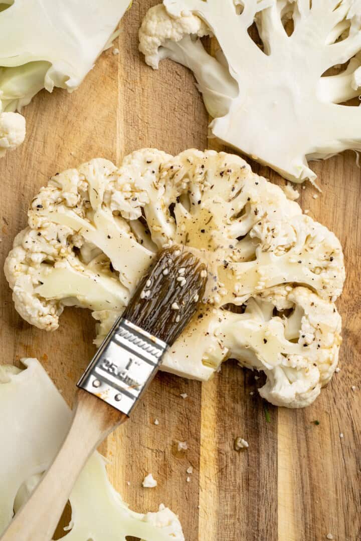 Brushing seasoning mixture onto cauliflower steaks