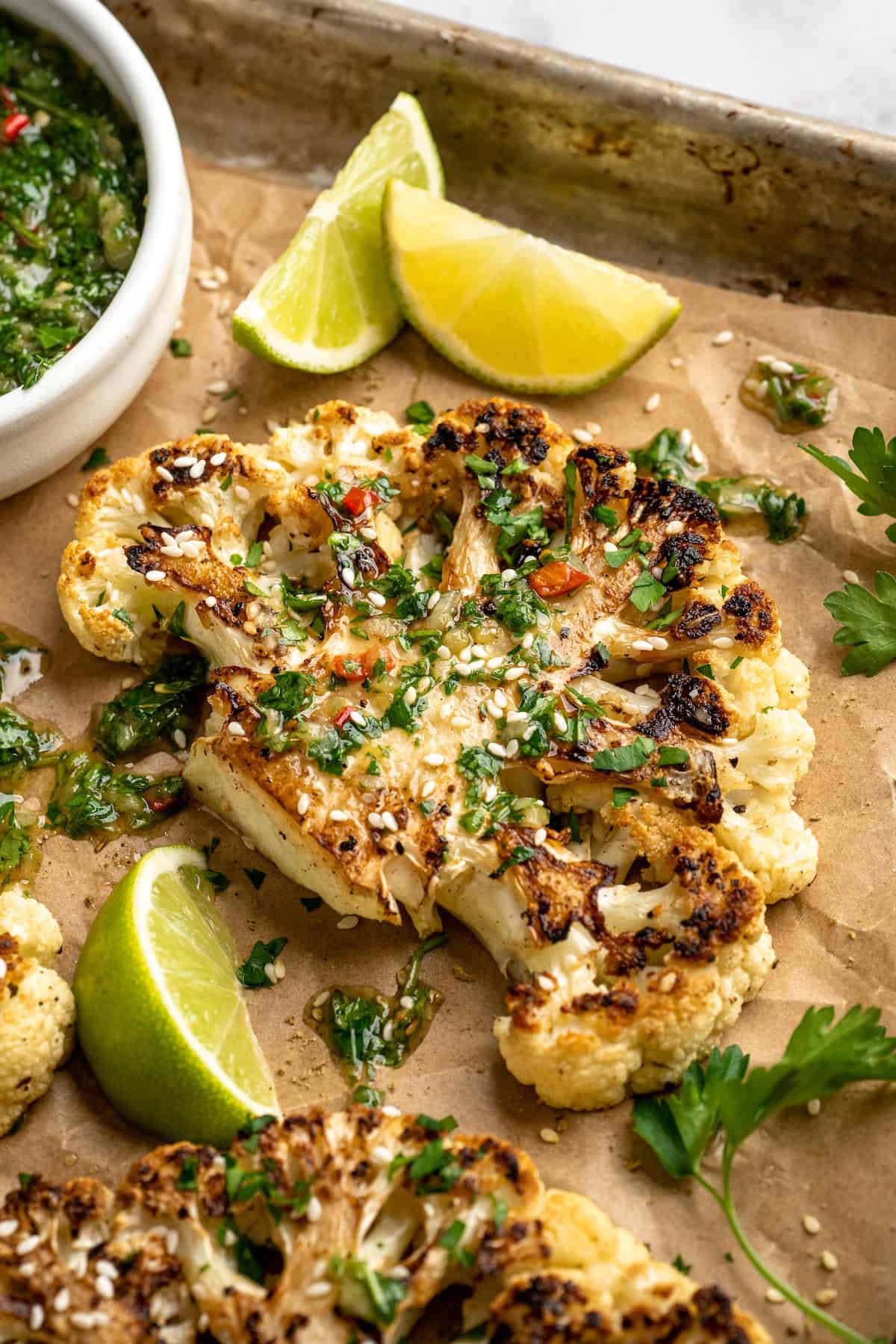 These easy roasted cauliflower steaks are tender, crispy on the edges, and incredibly flavourful thanks to the addition of za’atar! Cauliflower steak on sheet pan with chimichurri