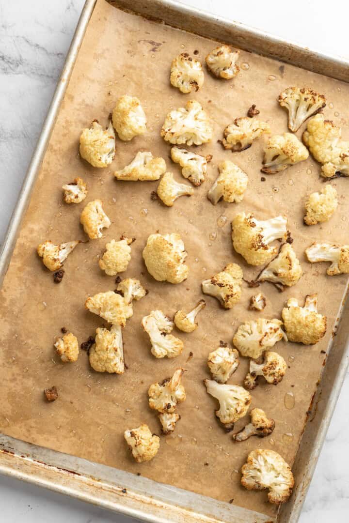 This easy Roasted Cauliflower Hummus gives the classic dip a low-carb makeover! I add roasted garlic too, which makes it extra delicious. Overhead view of roasted cauliflower on sheet pan