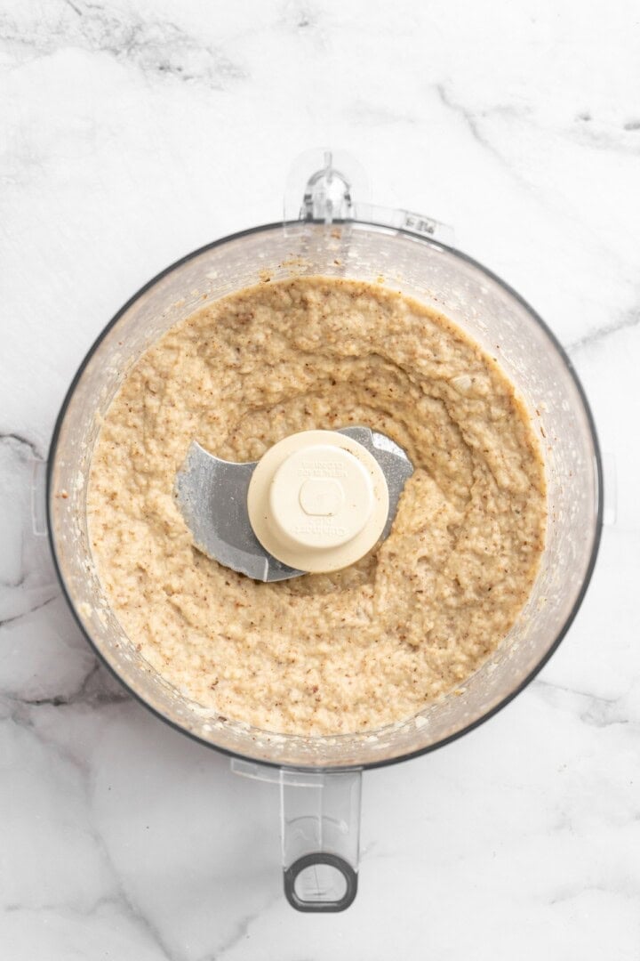 This easy Roasted Cauliflower Hummus gives the classic dip a low-carb makeover! I add roasted garlic too, which makes it extra delicious. Overhead view of pureed cauliflower in food processor