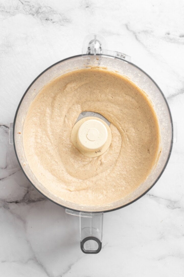 This easy Roasted Cauliflower Hummus gives the classic dip a low-carb makeover! I add roasted garlic too, which makes it extra delicious. Overhead view of roasted cauliflower hummus in food processor