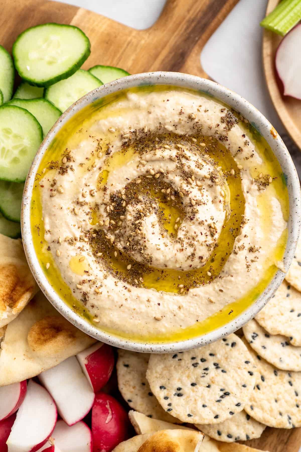 This easy Roasted Cauliflower Hummus gives the classic dip a low-carb makeover! I add roasted garlic too, which makes it extra delicious. Overhead view of roasted cauliflower hummus with olive oil and za'atar