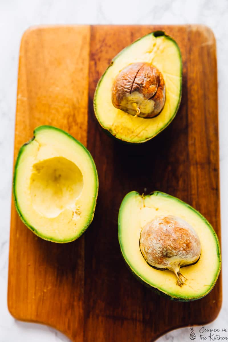 Top down shot of avocado halves on a wood board.