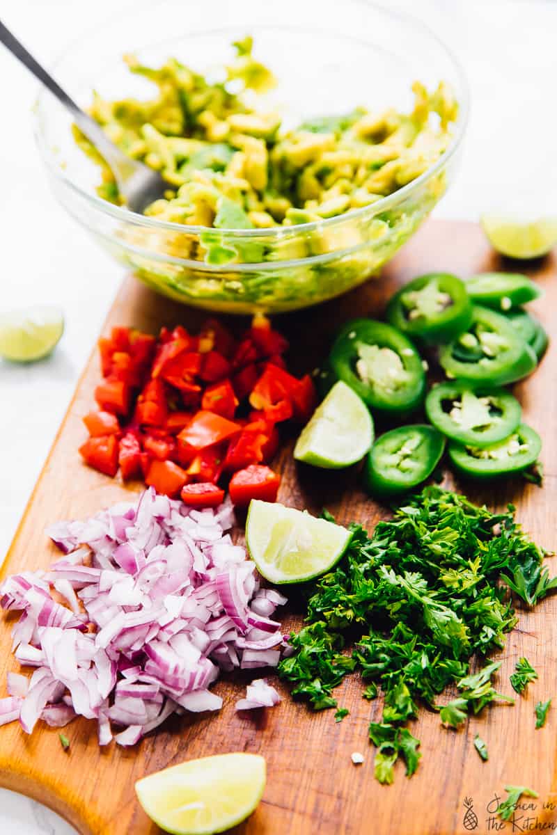 Chopped onions, jalapenos, cherry tomatoes and cilantro on a wood board. 