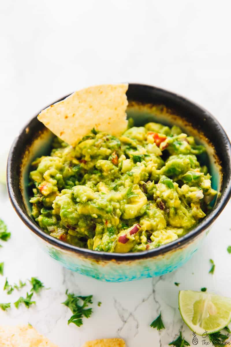 A tortilla chip dipped into a bowl of guacamole.