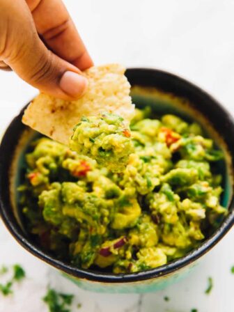 A bowl of guacamole with a chip dipped in.