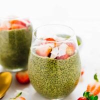 Close up photo of a bright green matcha chia pudding, surrounded by slices strawberries.