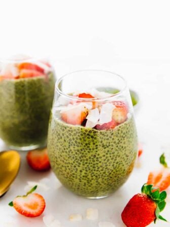 Close up photo of a bright green matcha chia pudding, surrounded by slices strawberries.
