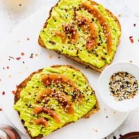 Top down shot of avocado toast on a white marble board.