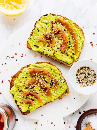 Top down shot of avocado toast on a white marble board.