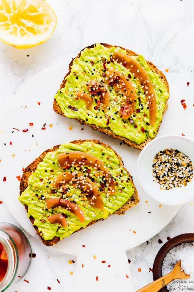 Top down shot of avocado toast on a white marble board.