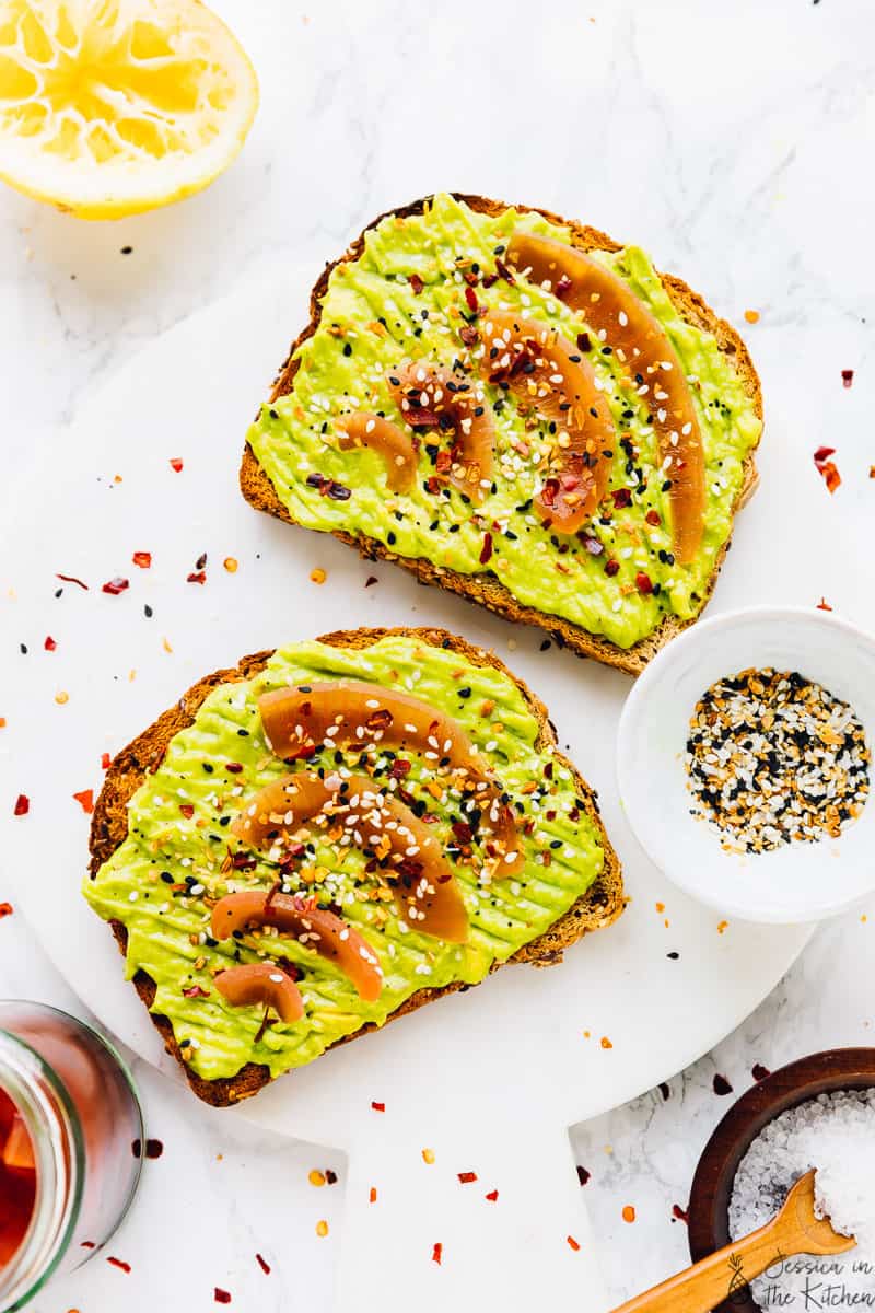 Avocado toast with pickled onions on a white marble board.