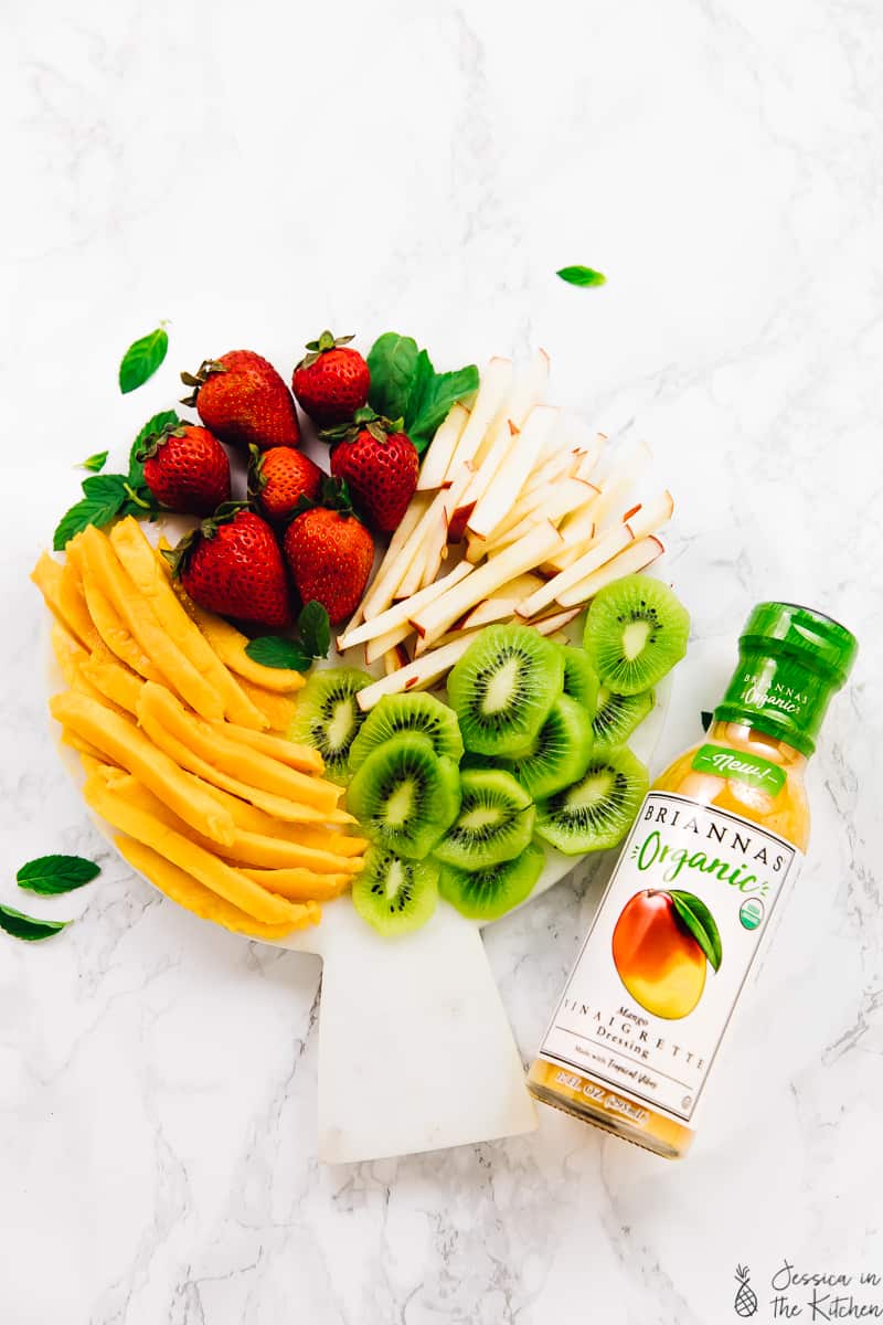 Overhead shot of sliced fruit and a bottle of dressing. 