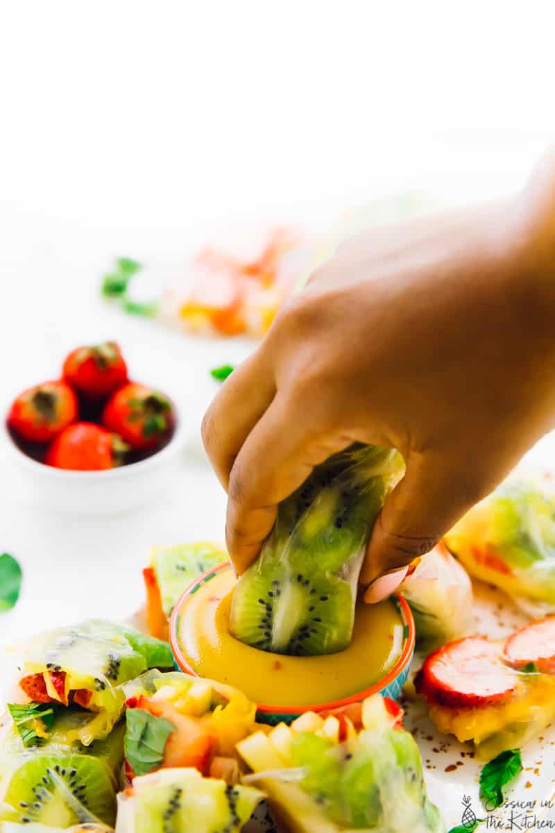 Dipping a summer fruit spring roll into dipping sauce. 