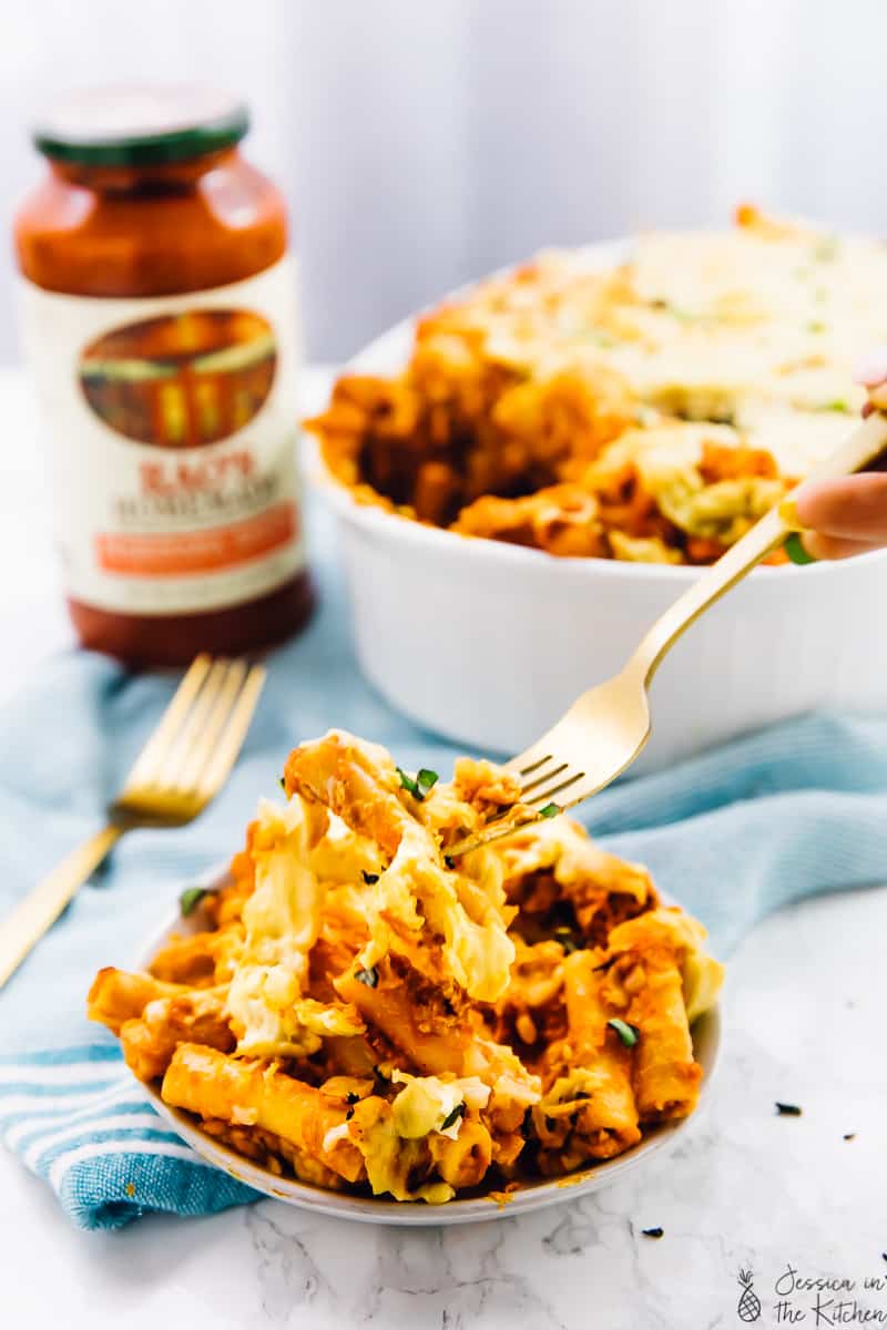 a fork digging into a bowl of baked ziti. 