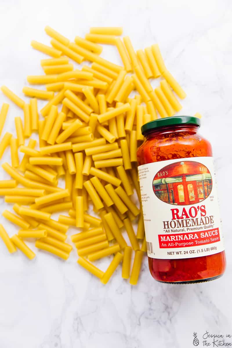 Top down shot of dry ziti pasta with a bottle of rao's homemade tomato sauce.