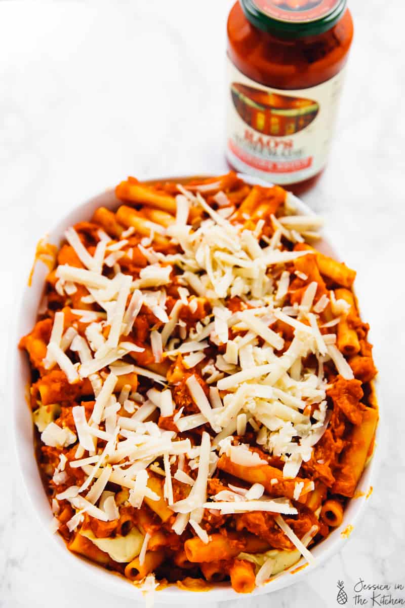 Pasta covered in tomato sauce and shredded cheese, in a baking dish.