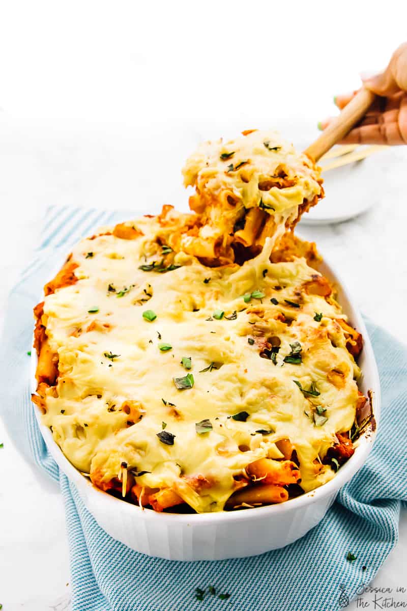 Photo of a vegan cheese baked pasta being pulled out of the serving dish with a cheese pull.