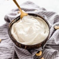 A spoon dipping into a bowl of cashew cream.
