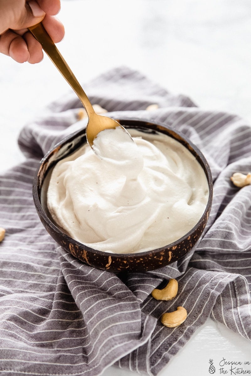 A bowl of cashew cream with a spoon lifting some out.