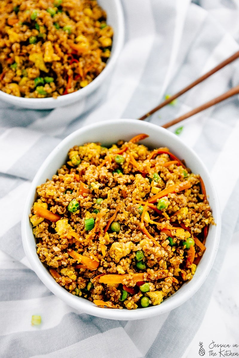 Overhead view of vegan quinoa fried rice in a bowl with chopsticks on the side. 