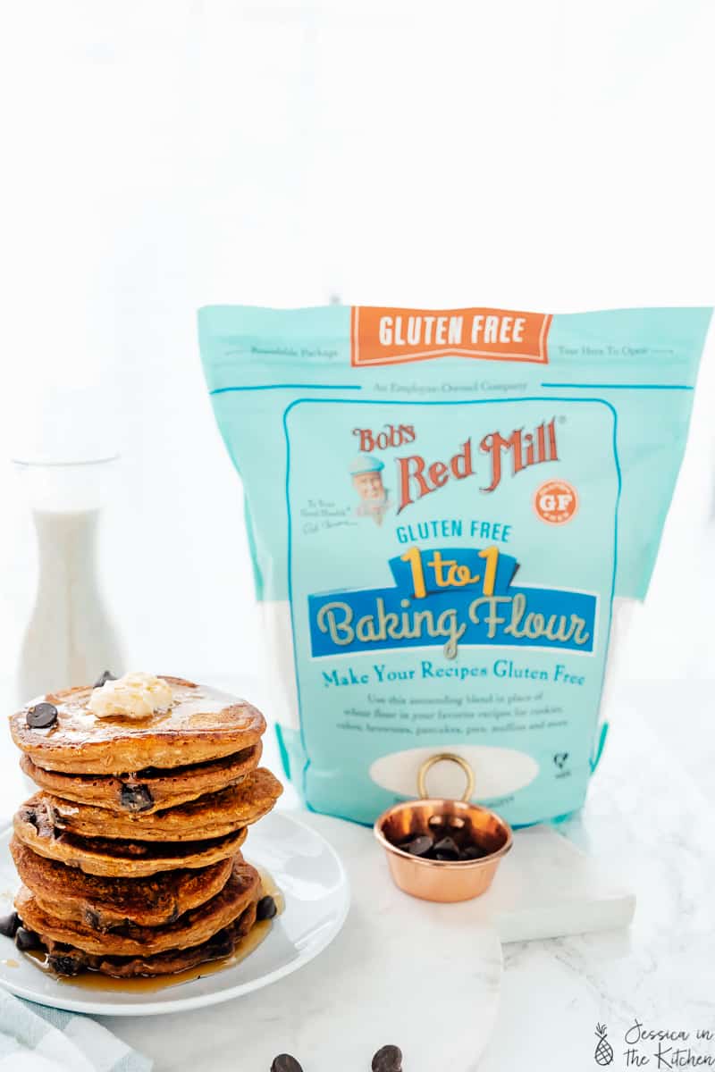 A stack of chocolate chip pancakes next to baking flour. 