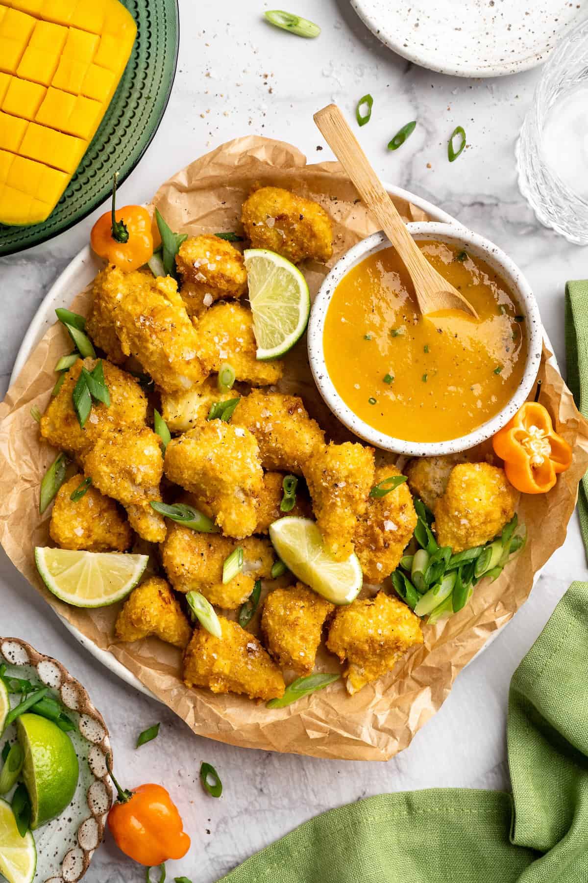 Overhead view of large platter of mango habanero cauliflower wings with bowl of sauce