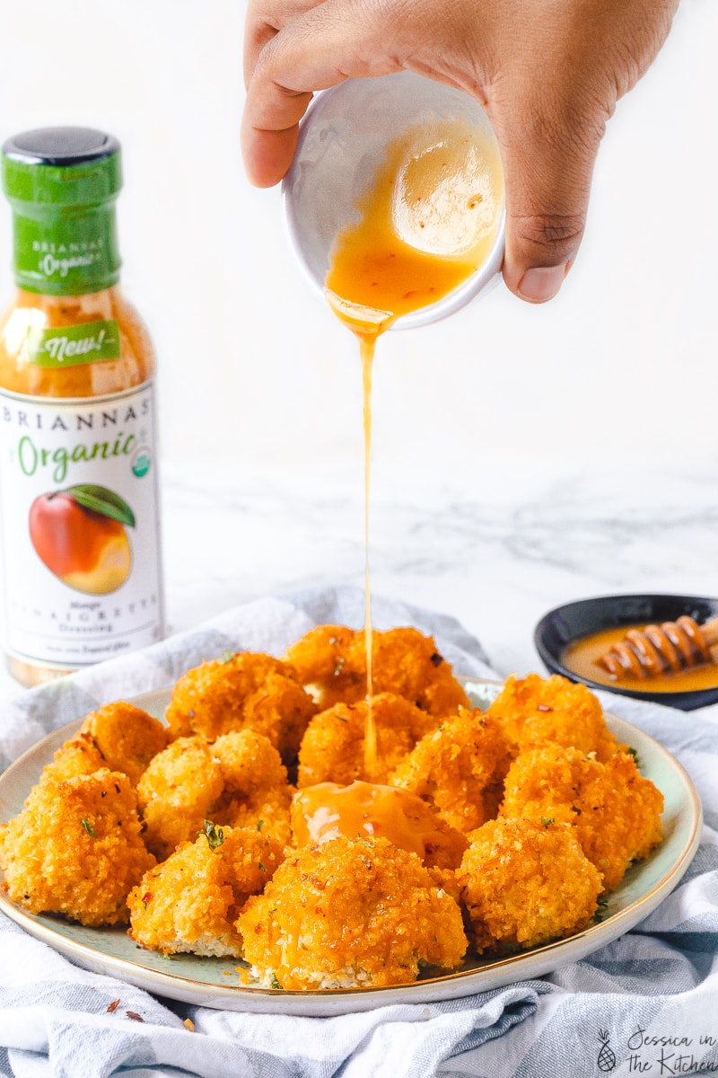Mango sauce being drizzled onto a plate of cauliflower wings.
