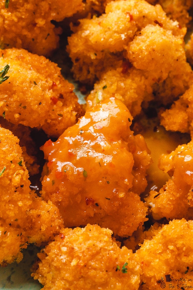 Close up of cauliflower wings with an orange mango sauce on them.