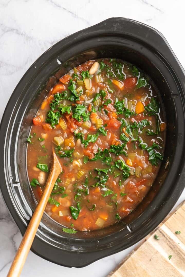 Overhead view of white bean and kale soup in slow cooker