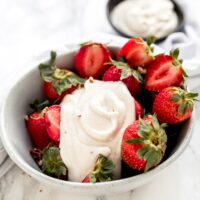 Cashew whipped cream on a bowl of fresh strawberries.