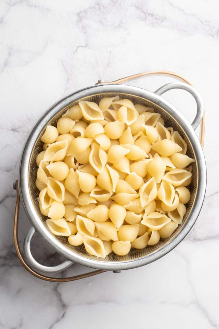 Overhead view of cooked pasta shells in colander