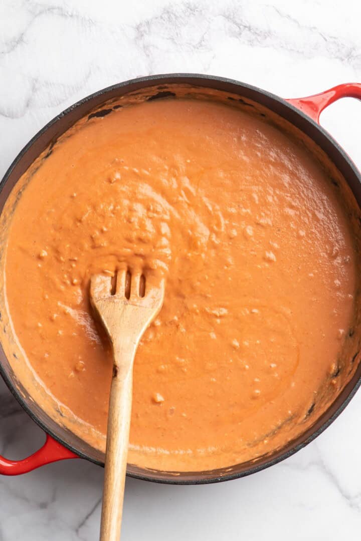 Stirring vegan creamy tomato sauce in skillet